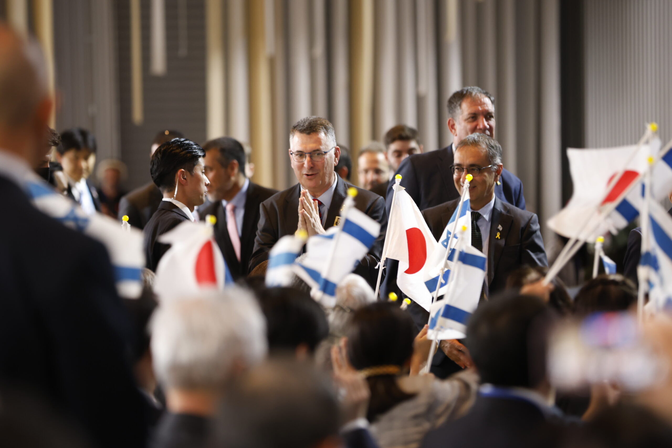 入場する人たちを国旗を振って迎える観客